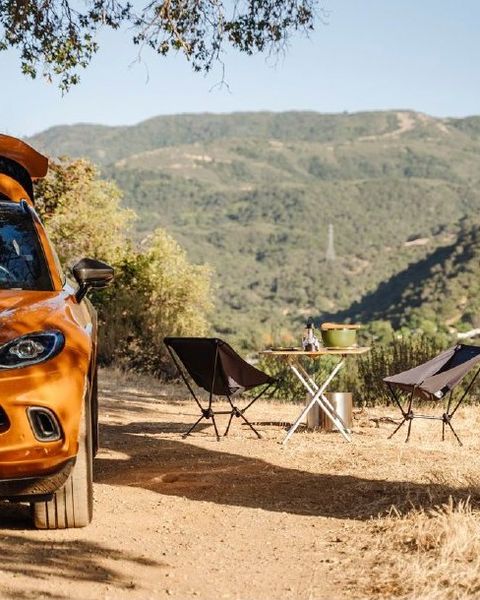 An Aston Martin DBX in Golden Saffron beside a camp set up in the California hills