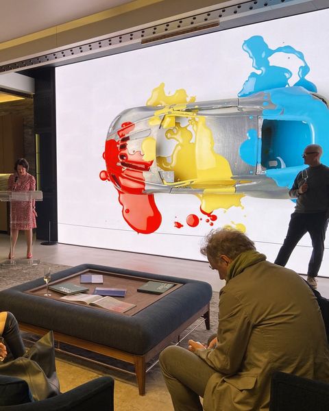 Guests at an ILN and Aston Martin evening, in front of a screen showing a car splashed with red, yellow and blue paint